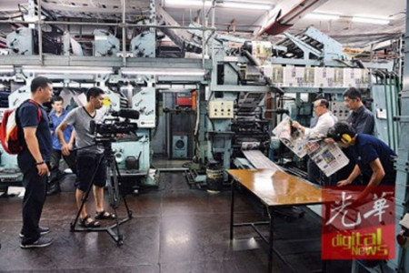 （左起）邱智堅、林星發(fā)及李興前觀察剛出爐的報紙。（馬來西亞《光華日報》）