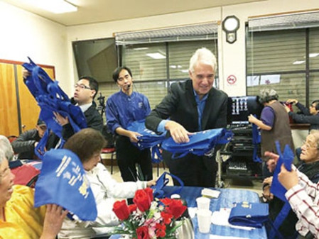 地方檢察長賈斯康(中)到日落區(qū)安老自助處派發(fā)防金光黨環(huán)保袋。(美國《世界日報》／李秀蘭 攝)