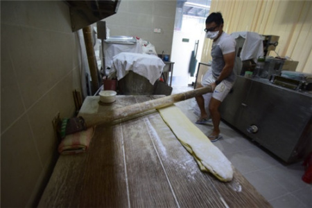 賴銘康示范用祖?zhèn)鲹{面杖搟面，并指手工才能讓面團均勻受力，制出的面條才有彈性。(馬來西亞《星洲日報》)