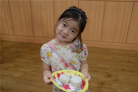 一個小女孩開心地展示自己親手做好的月餅 一個小女孩開心地展示自己親手做好的月餅