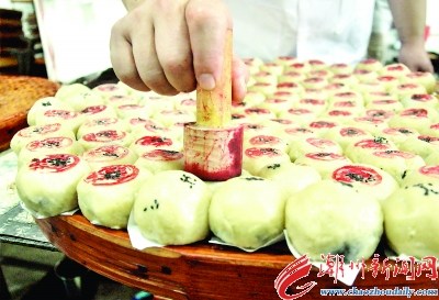 在生餅皮上面綴上黑芝麻，底部墊上白紙片后平整擺放。按傳統(tǒng)慣例，在生餅皮上蓋上鋪號印章。