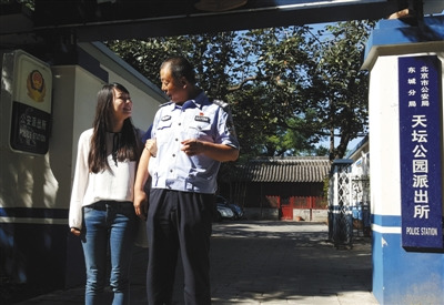 9月19日上午，天壇公園派出所門口，菲菲挽著民警侯祥煒的胳膊。22年前，侯祥煒接群眾報警，從公園南門東側(cè)的一棵柏樹下，將被遺棄的菲菲抱回。(圖片來源：新京報)