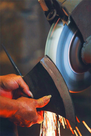 鐵菜刀的鋒口在砂輪的打磨下，漸露鋒芒。