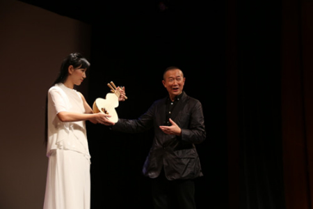 譚盾(右)介紹藉由敦煌古畫(huà)而還原出的“反彈琵琶”所用樂(lè)器。(美國(guó)《世界日?qǐng)?bào)》/洪群超 攝) 