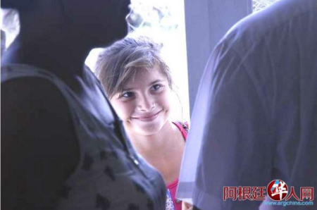 Magali透過人縫偷偷的看著愛心人士，滿心喜悅。（阿根廷華人網(wǎng)）