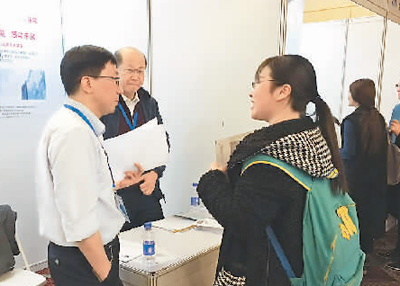 在一家公司的展臺(tái)前，一名應(yīng)聘者正在向用人單位咨詢招聘崗位相關(guān)信息。