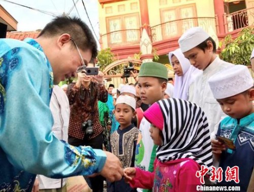 圖為顧景奇向孤兒和貧困兒童發(fā)放禮包?！∏貫榉?攝