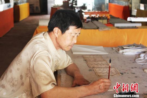 在甘肅敦煌市的一處民俗旅游地——月牙泉小鎮(zhèn)內(nèi)，傅有宏伏案臨摹敦煌漢簡?！⌒煅?攝