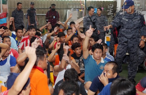 移民局官員詢問是否擁有護(hù)照時，許多外勞舉起手。(馬來西亞《星洲日報》)