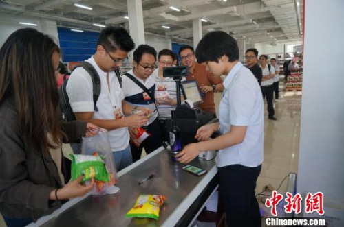 圖為華裔青年排隊為購買的進口商品付賬?！№n章云 攝