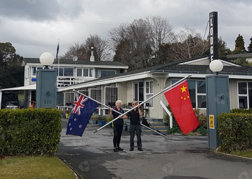  Jenkins夫婦在旅館門口手持中新兩國國旗，拍下這張照片。（新西蘭天維網(wǎng)）