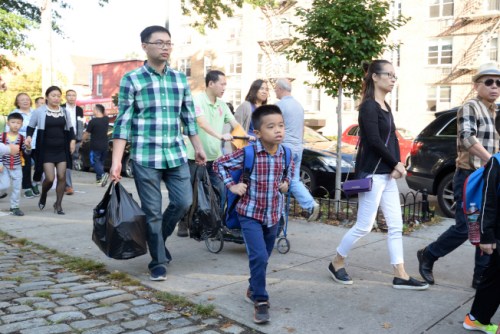 華裔家長(zhǎng)當(dāng)起“挑夫”，拎著大包小包文具帶孩子上學(xué)。（美國(guó)《世界日?qǐng)?bào)》/朱澤人 攝）