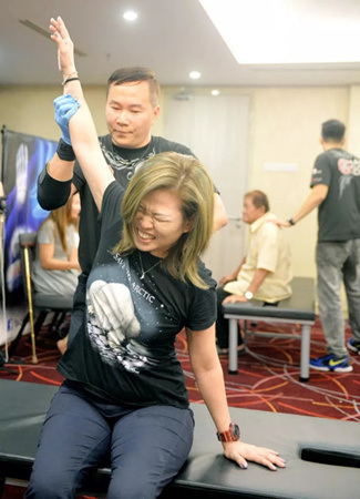 梁潤江為獅城客萬鳳儀進(jìn)行五十肩的治療。（馬來西亞《星洲日?qǐng)?bào)》）