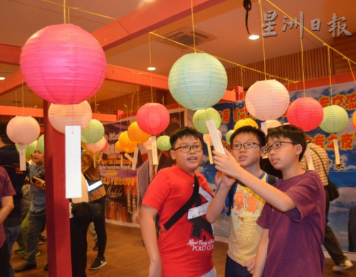 青少年對(duì)猜燈謎產(chǎn)生了興趣，共同思考找答案。（馬來西亞《星洲日報(bào)》）