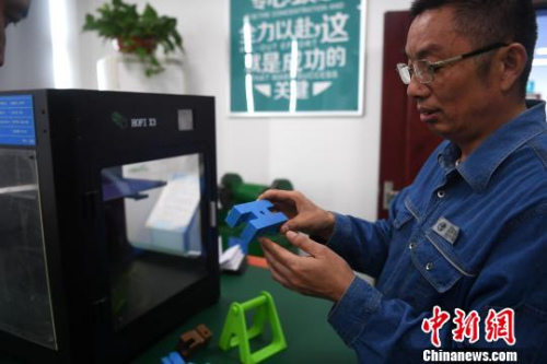 許啟金在工作室中利用3D打印機制作模具?！№n蘇原 攝