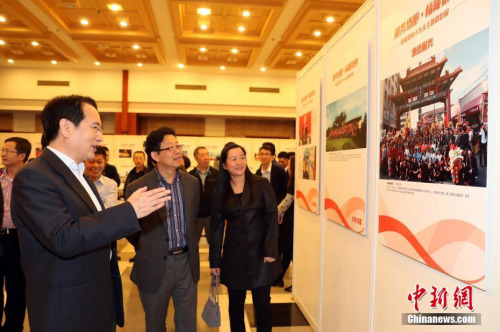10月13日，國務(wù)院僑務(wù)辦公室副主任譚天星（左）在北京參觀“服務(wù)僑胞·情暖僑心”——迎接黨的十九大主題攝影展，該展覽由國務(wù)院僑務(wù)辦公室主辦，中國新聞社圖片網(wǎng)絡(luò)中心承辦。 <a target='_blank' >中新社</a>記者 張宇 攝