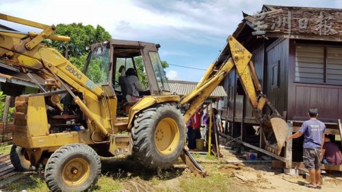 人力不足，丹土生華裔協(xié)會出動挖泥車助力。（馬來西亞《星洲日報》） 葉興再（右）發(fā)號司令，和村民各就各位，移動房子。（馬來西亞《星洲日報》）