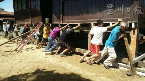 村民守望相助，重現(xiàn)人力搬動房子的風(fēng)俗。（馬來西亞《星洲日報》）