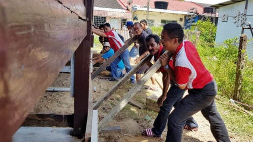 葉興再（右）發(fā)號司令，和村民各就各位，移動房子。（馬來西亞《星洲日報》）