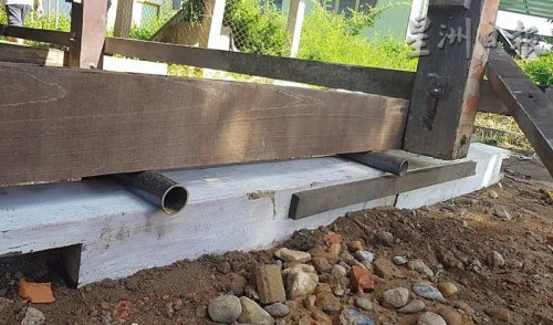 工匠在屋子下方的柱子四周架上木條，再使用圓形鐵管的滾動原理，對房子進行人力移動。（馬來西亞《星洲日報》）