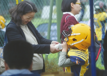 訓(xùn)練場邊的家長給自己的孩子喂水。