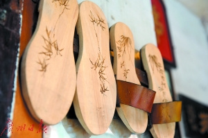 吳伯親手在木屐上鉻畫。