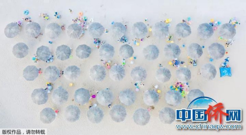 “相機(jī)攝”江蘇連云港市蘇馬灣海濱浴場，游客們在遮陽傘下悠閑休息。