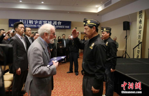 12月10日下午，美國舊金山中華文化中心，中英文口號聲不斷響起，由南京大屠殺索賠聯(lián)盟、舊金山灣區(qū)中國統(tǒng)一促進(jìn)會、舊金山抗日史實(shí)維護(hù)會和慰安婦正義聯(lián)盟聯(lián)合主辦的“南京祭”紀(jì)念活動進(jìn)入第21年。圖為中國駐舊金山代總領(lǐng)事查立友（左一）、南京大屠殺索賠聯(lián)盟前主席羅杰斯·斯科特（左二）接受美國退伍軍人協(xié)會華系支會轉(zhuǎn)交美國國旗。<a target='_blank' >中新社</a>記者 劉丹 攝