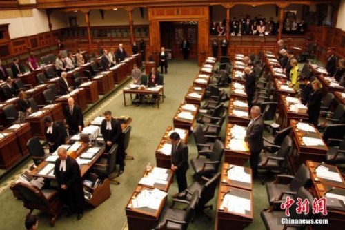 在南京大屠殺80周年之際，當?shù)貢r間12月13日，加拿大安大略省省議會舉行南京大屠殺紀念活動。圖為安省議會議事大廳內全體起立，為南京大屠殺數(shù)十萬死難者默哀。<a target='_blank' >中新社</a>記者 余瑞冬 攝