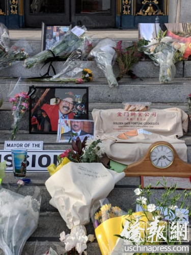 臺(tái)階上擺放著鮮花和李市長(zhǎng)喜愛(ài)的金門(mén)餅家簽語(yǔ)餅和寫(xiě)著紀(jì)念語(yǔ)的T恤。(僑報(bào)記者陳勇青攝)