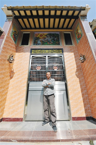 潘先良與其繪制的民居壁畫(huà)合影。 海南日?qǐng)?bào)記者 袁琛 攝