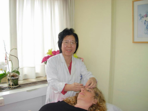 資料圖：李洪芬為當?shù)鼗颊咧委?(圖片來源：國際在線)