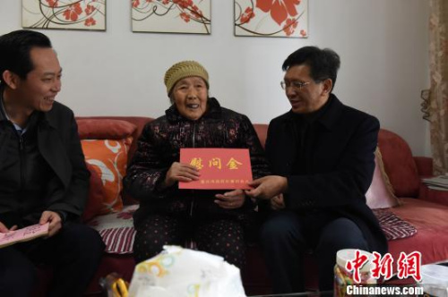 圖為重慶市人民政府外事僑務(wù)辦公室黨組書記、主任吳康明向南僑機工遺孀盈明英送上慰問金?！≈芤?攝