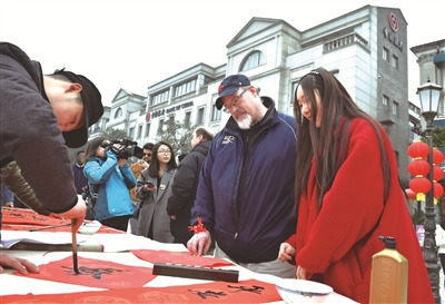 書法家揮毫潑墨，現(xiàn)場送春聯(lián)，老外看得津津有味。 (嚴(yán)龍 張昊樺 攝)