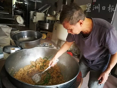王振隆以大鍋翻炒香噴噴的椰絲佐料。(馬來(lái)西亞《星洲日?qǐng)?bào)》記者/李慧婷 攝)