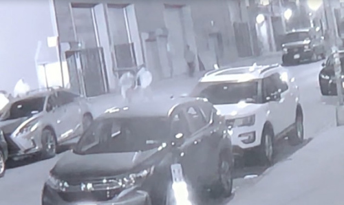 一華裔男子手捂腹部被人扶上汽車。