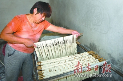 醒面：各握住兩根面桿的一端，將面線往兩邊稍微撐長點(diǎn)，又沾些木茨粉，靜置在面柜上“醒面”。