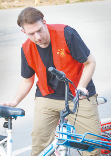 2018年4月2日，布萊恩·基斯在浙江省湖州市吳興區(qū)參加志愿服務活動。圖為他正在整理亂停放的共享單車。 　　黃麗榮攝