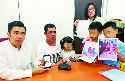 許羅全與3名稚齡子女盼望鄧春美早日回家團(tuán)聚。左為方美錸、右為王育璇。(圖片來源：馬來西亞光華網(wǎng))