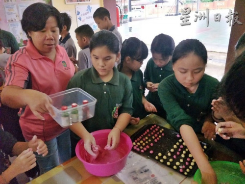 莊美玉（左）指導(dǎo)學(xué)生搓湯圓。（馬來西亞《星洲日報》）