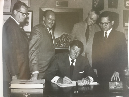 當(dāng)時還是州長的里根(Ronald Reagan)簽署譚卓儀(右一)的“教育補償計劃”提案。(圖片來源：譚卓儀提供)