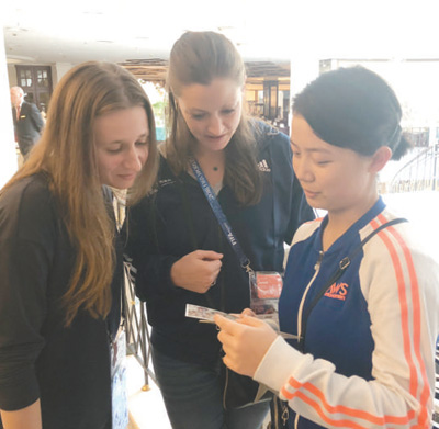 　護旗手汪美侖(右一)在用自己制作的貴州風(fēng)光明信片介紹家鄉(xiāng)。 