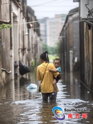 9月2日，陳店鎮(zhèn)北溝村，水位開始退去，一名大人帶著孩子蹚水回家。南方網(wǎng)全媒體記者 張由瓊 實習(xí)生 徐杰 攝