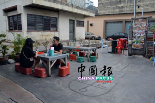 在祖屋前，與三兩好友蹲坐小凳存吃著鮮蛤，別具風(fēng)味。(馬來西亞《中國報(bào)》記者 趙詩綺 攝)