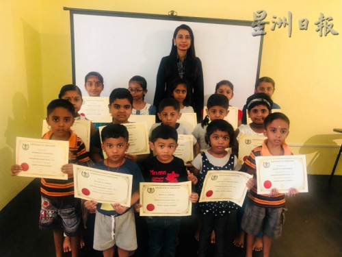 在完成了一個階段的學(xué)習(xí)后，孩童們開心地從普麗緹(后排中)手中接過“畢業(yè)證書”。(馬來西亞《星洲日報》)