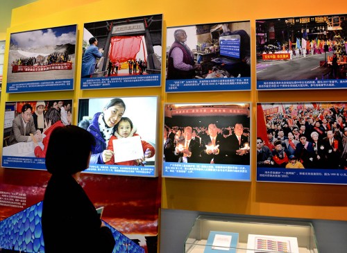 一位參觀者在“海外僑胞心系祖國(guó) 助力改革開(kāi)放”展廳，觀看“2005年5月，第三屆世界華僑華人社團(tuán)聯(lián)誼大會(huì)與會(huì)代表舉行燭光祈愿儀式，表達(dá)‘反獨(dú)促統(tǒng)’心聲”等展覽照片。（《芝加哥華語(yǔ)論壇》/張大衛(wèi) 攝）