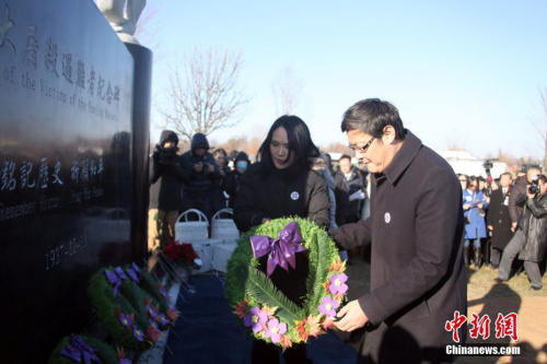當?shù)貢r間12月9日，由當?shù)厝A僑華人籌資修建的南京大屠殺遇難者紀念碑在加拿大多倫多揭幕。這座由多倫多華人團體聯(lián)合總會與加拿大中國洪門民治黨多倫多支部共同發(fā)起修建的紀念碑坐落在大多倫多地區(qū)列治文山的愛恩墓園內(nèi)，坐西朝東。圖為加拿大華人國會議員譚耕（右）、關慧貞向紀念碑獻花。<a target='_blank' >中新社</a>記者 余瑞冬 攝