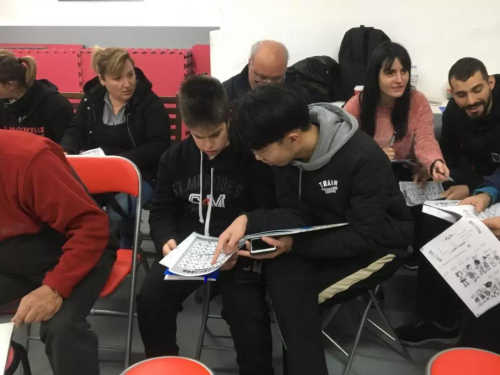 志愿者黃承輝(前排右一)輔導(dǎo)學(xué)員漢語(yǔ)拼音。(《歐洲時(shí)報(bào)》/蘇珊娜 攝)