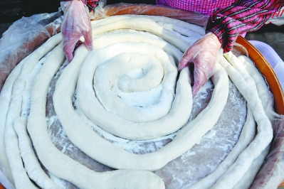 林傳星的妻子孫巧瑤把麥芽糖包裹酥脆的花生等配料揉搓拉成條狀，再用剪子斜剪成塊狀。