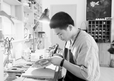 王建榕在專心致志地鋦瓷。